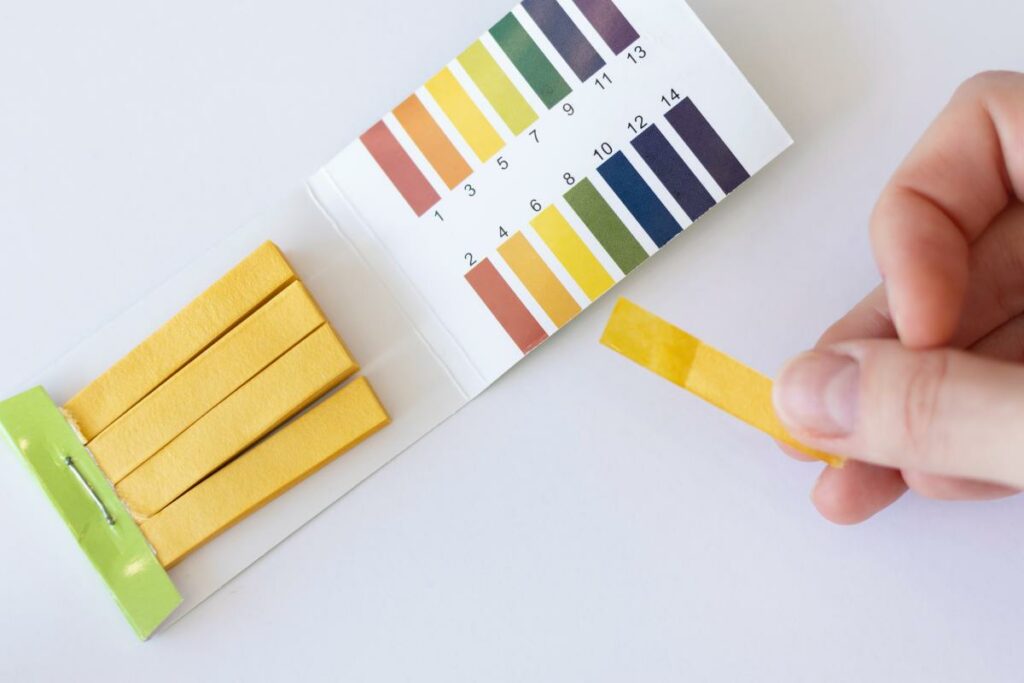 Water pH measurement test. Yellow strip in a womans hand.